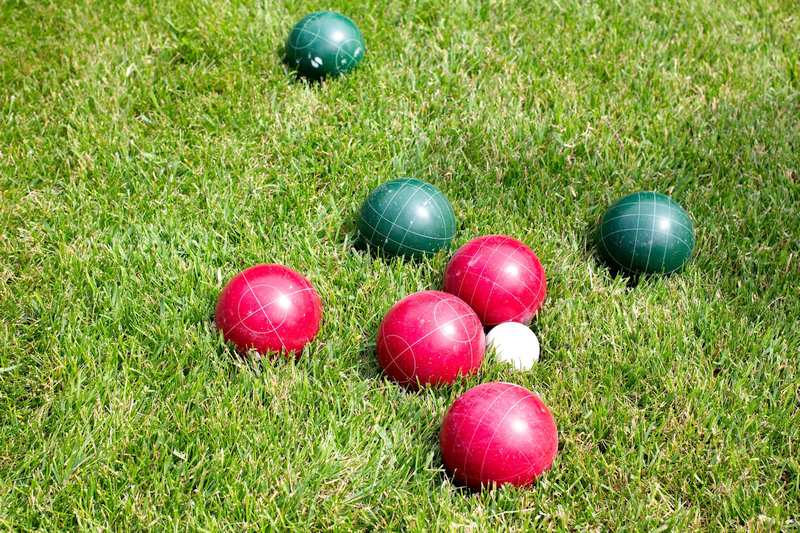 Red and green Bocce balls laying in the grass.